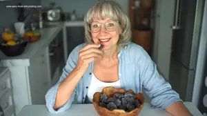 Susan Gast enjoying a dried plum from a wooden bowl filled with homemade dehydrated plums