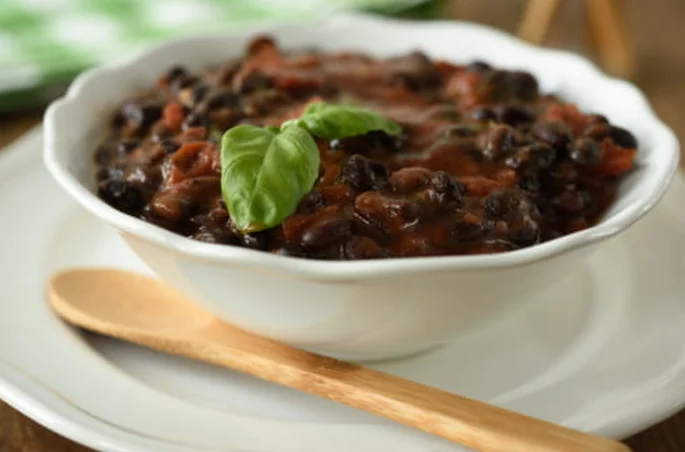 Black bean soup topped with mint sprig, in a white bowl