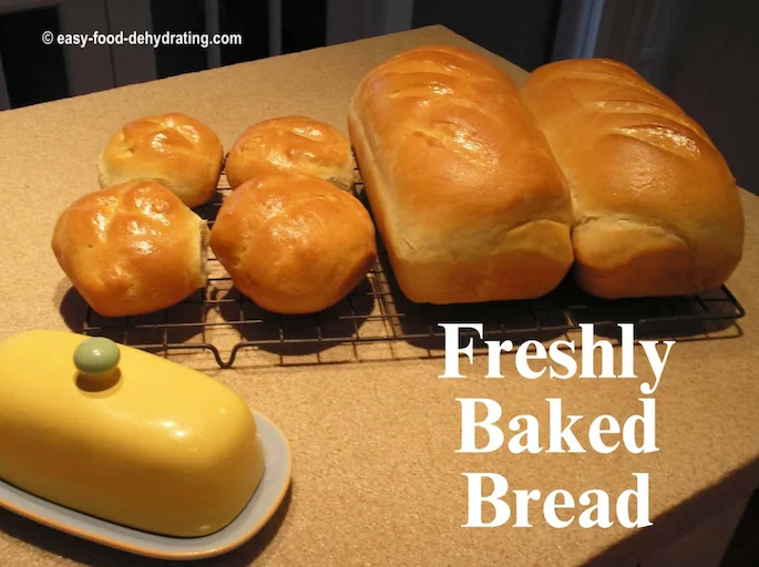 freshly baked bread cooling on the countertop - ready to take a bite? Freshly baked bread, 2 loaves and four buns cooling, butter dish