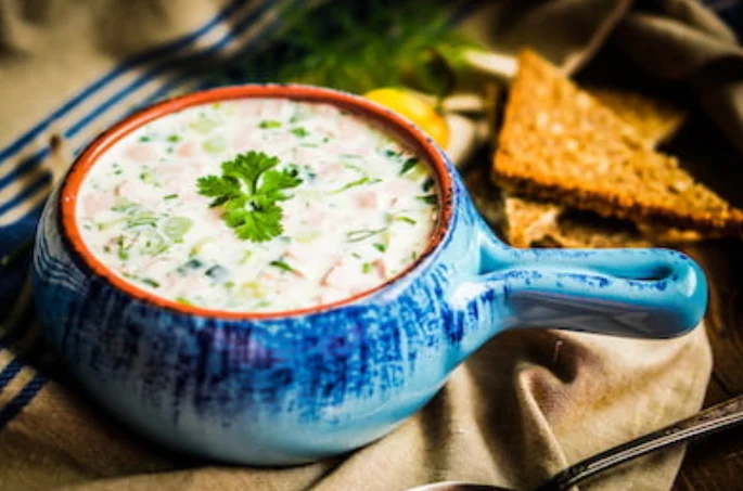 Dehydrated broccoli, carrot, and cheese soup served in a bowl A pretty blue earthenware bowl filled with creamy broccoli soup with added carrot, and a sprig of parsley.