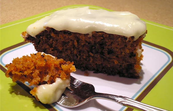 Slice of homemade carrot cake with cream cheese frosting on a plate