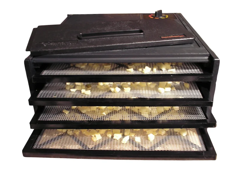 Black Excalibur 4-tray food dehydrator with diced potatoes spread across mesh trays.