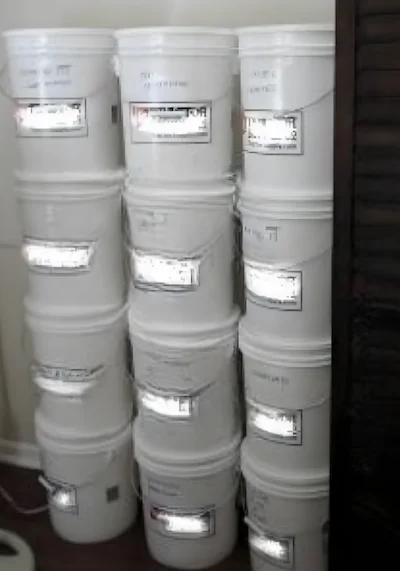 Stack of white 5-gallon food-grade #2 plastic buckets with lids used for long-term food storage