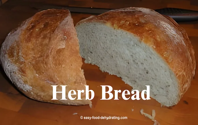 Freshly-baked Herb Bread, loaf sliced in half, sitting on a wooden cutting board