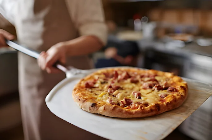 freshly baked pizza on a pizza paddle freshly baked pizza on a pizza paddle