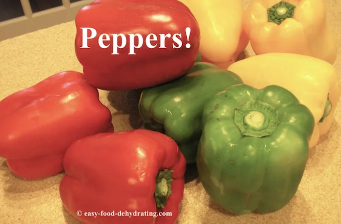 Red, green, and yellow peppers on a countertop.