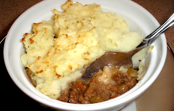 Shepherd’s pie in a white ramekin topped with golden mashed potatoes