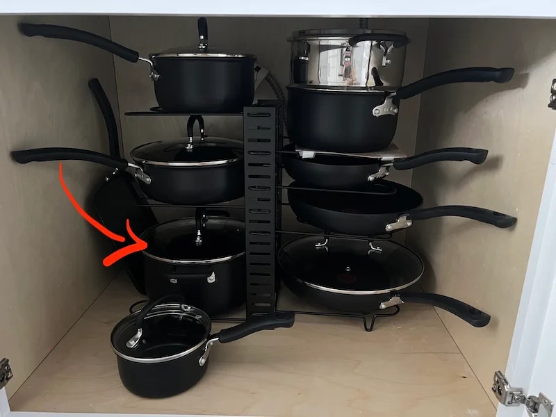 Susan’s T-fal 17-piece hard-anodized cookware set stored beneath her cooktop, with a red arrow pointing to the 5-quart Dutch oven she uses for soups and stews.