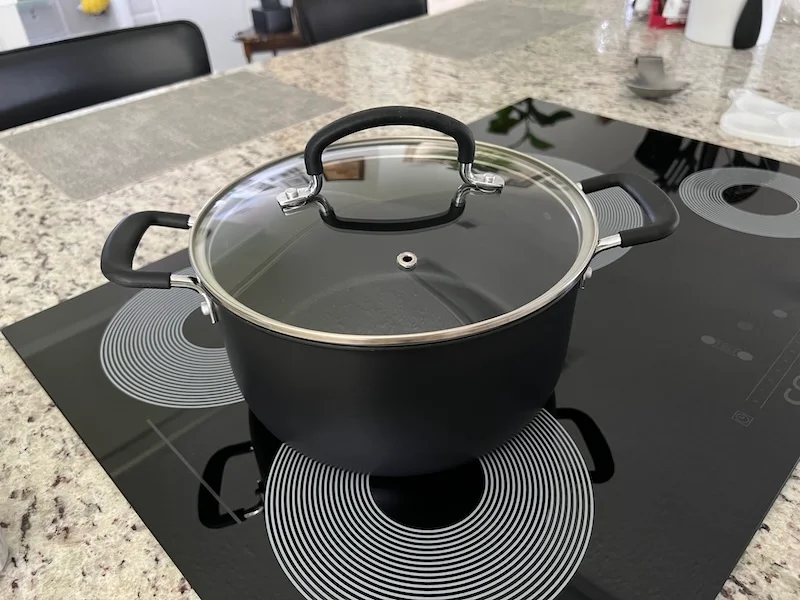 Susan’s 5-quart T-fal hard-anodized Dutch oven with a glass lid, sitting on her kitchen cooktop.